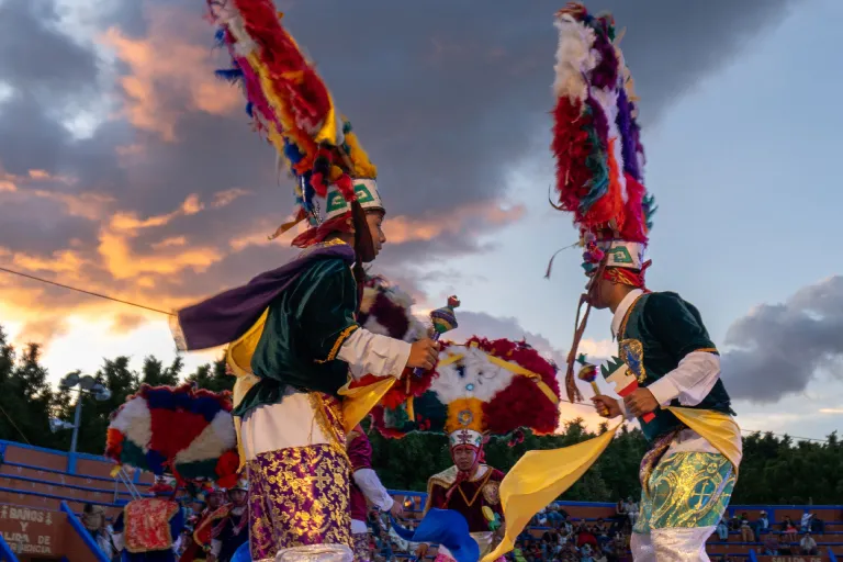 Hero main image of Guelaguetza del Tule festival in Santa María del Tule, Oaxaca, showing a vibrant scene of dancers in traditional costumes performing on stage with a lively audience